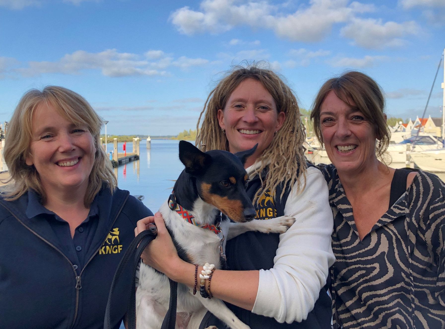 Trainsters Patricia, Renske en Petra poseren samen met een hond in de armen