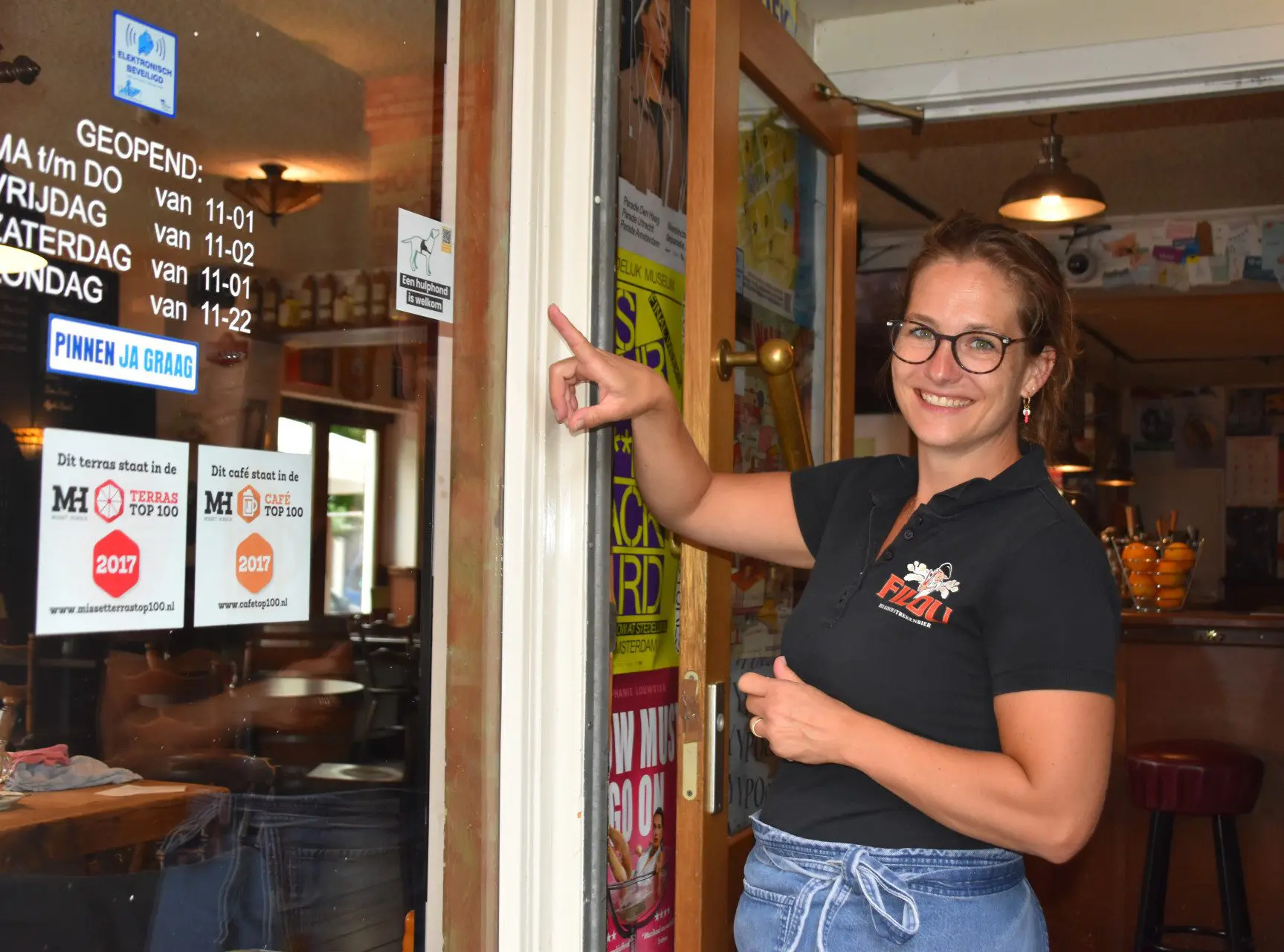 Een werknemer van een cafe wijst naar een sticker die laat zien dat een hulphond is toegestaan