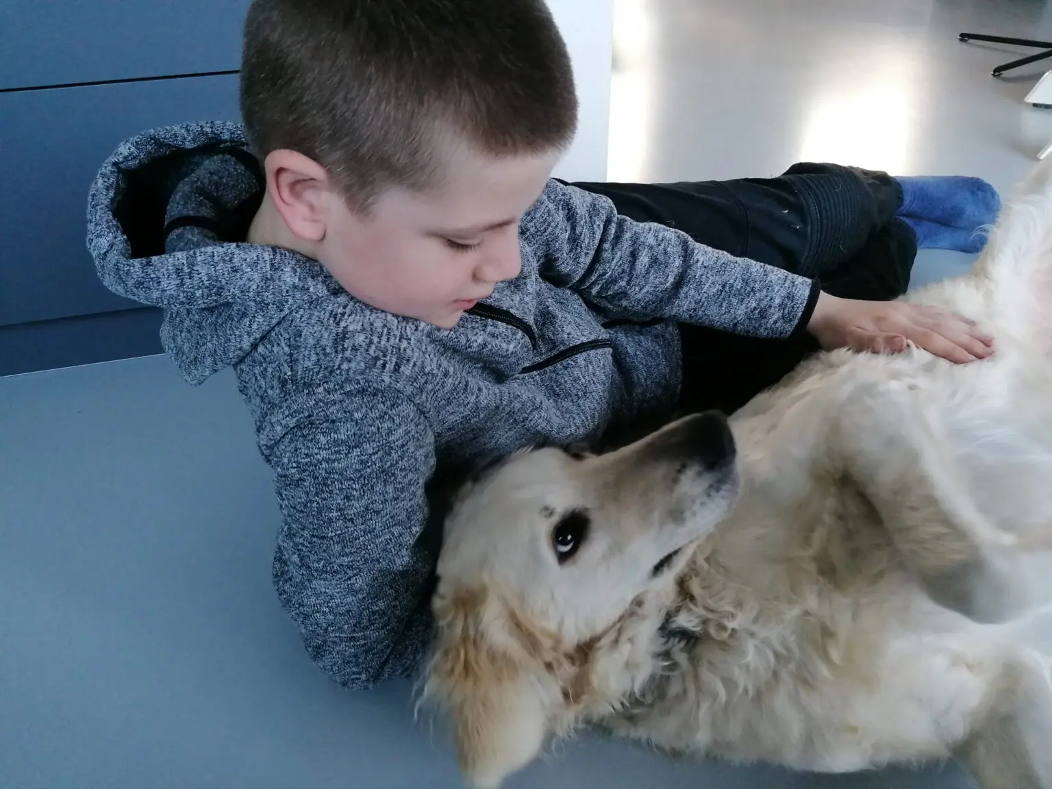 Jongetje ligt op de grond met naast hem labradoodle Bobbie