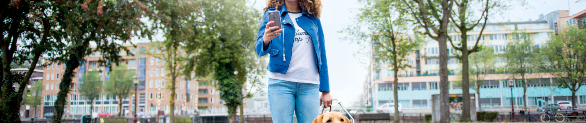 Beeld uit de campagnevideo Bennie Blind waarbij een meisje in de ene hand een mobiel vasthoudt en in de andere haar 'afgeleidehond' met blauw tuig