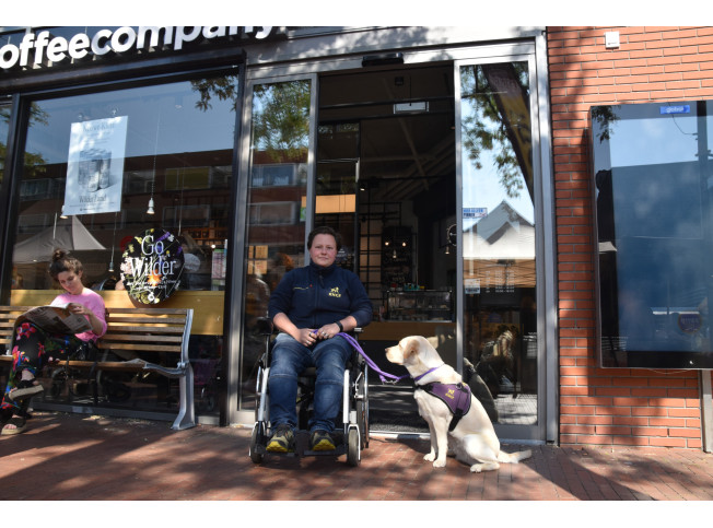 KNGF-trainer in rolstoel voor deur coffeecompany