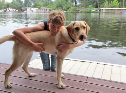 Jongetje knuffelt met hond aan het water