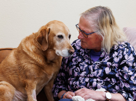 Mieke samen met haar assistentiehond Zonta op de bank