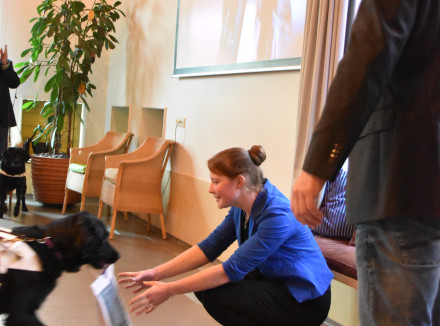 Larissa Klaassen zit op haar hurken en neemt het boek Vooraan in ontvangst van een blindengeleidehond in opleiding