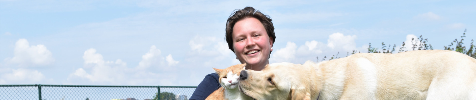 Priscilla met blonde labrador en kennelkat buiten op een speeltoestel