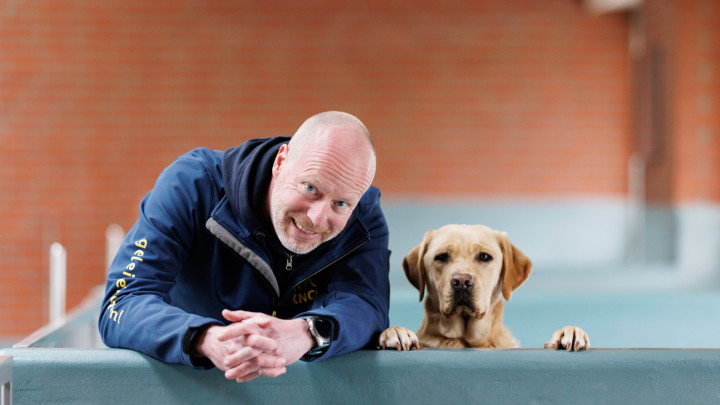 Collega ronald en een labrador kijken samen over een van de muurtjes in de kennel