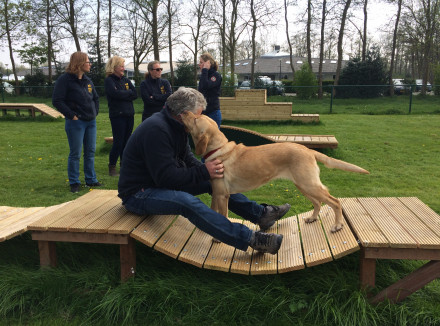 Hoofdinstructeur Kees Tinga en geleidehond in opleiding bij de nieuwe speel-en trainingstoestellen gesponsord door Rabobank Coöperatief Fonds en ING Nederland Fonds