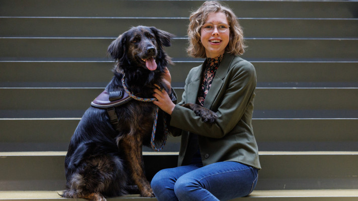 jonge vrouw zit op een trap met haar geleidehond naast zich