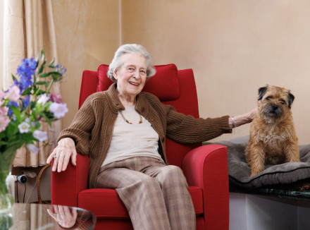 Portret van mevrouw in haar woonkamer met een hond naast haar