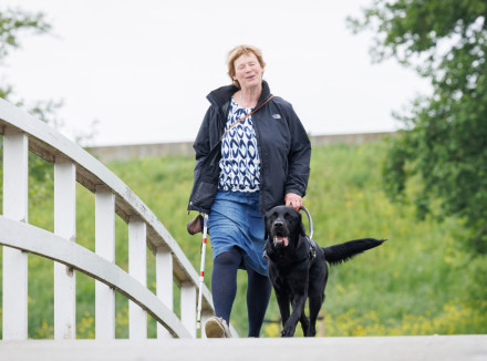 Clary en haar blindengeleidehond Flipse lopen over een brug