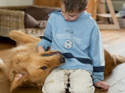 Jongetje knuffelend met zijn buddyhond autisme