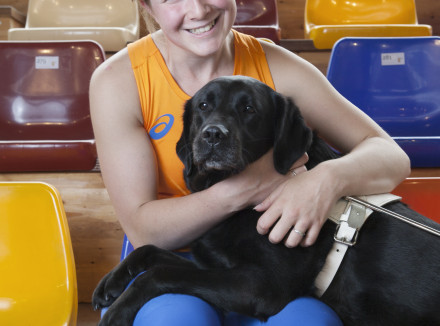 Larissa Klaassen op een sporttribune met haar blindengeleidehond