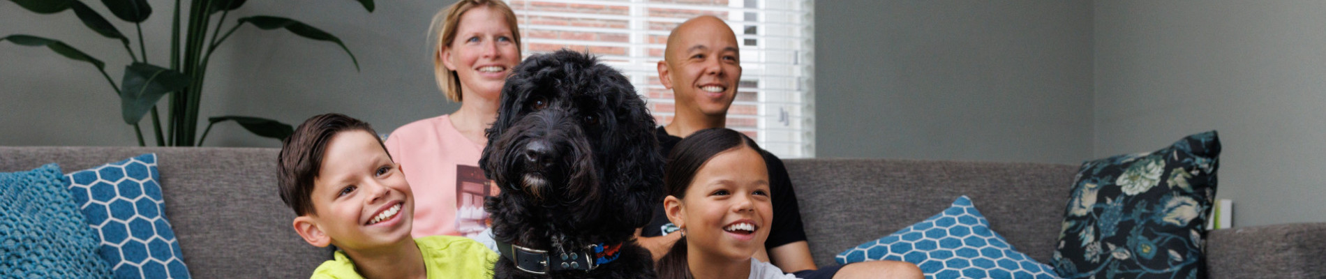 het gezin zit op de bank met hun hond in het midden