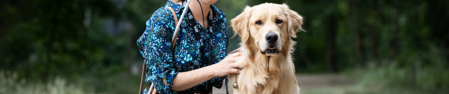 cliënt zit gehurkt naast een golden retriever in een bosrijke omgeving