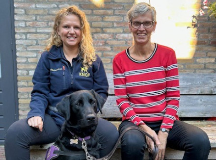 portret van pleegouder Atie, instructeur Bo en een zwarte hond