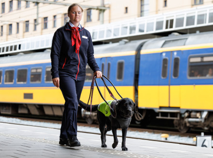 Anna loopt met haar geleidehond op het perron voor een trein langs