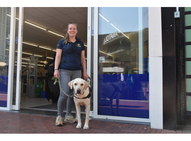KNGF-trainer staat met hond voor openbare gelegenheid