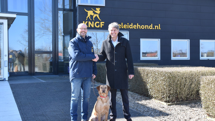 De afspraak wordt bezegeld met een hand voor het pand van KNGF Geleidehonden