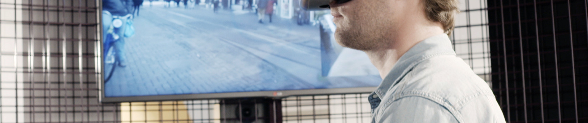 Man loopt met VR-bril op de loopband, op het scherm naast hem kun je meekijken met zijn zicht