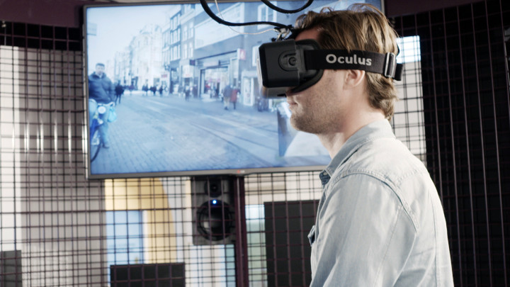 Man loopt met VR-bril op de loopband, op het scherm naast hem kun je meekijken met zijn zicht