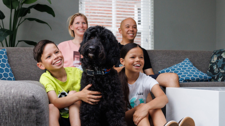 het gezin zit op de bank met hun hond in het midden