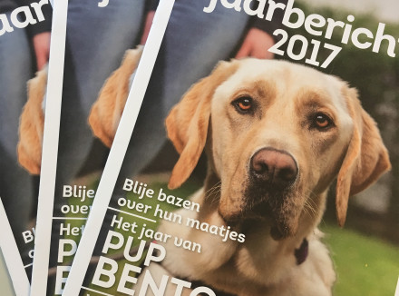 Het jaarbericht in magazinevorm met op de vooorkant de tekst 'Jaarbericht 2017' en een blonde labrador.