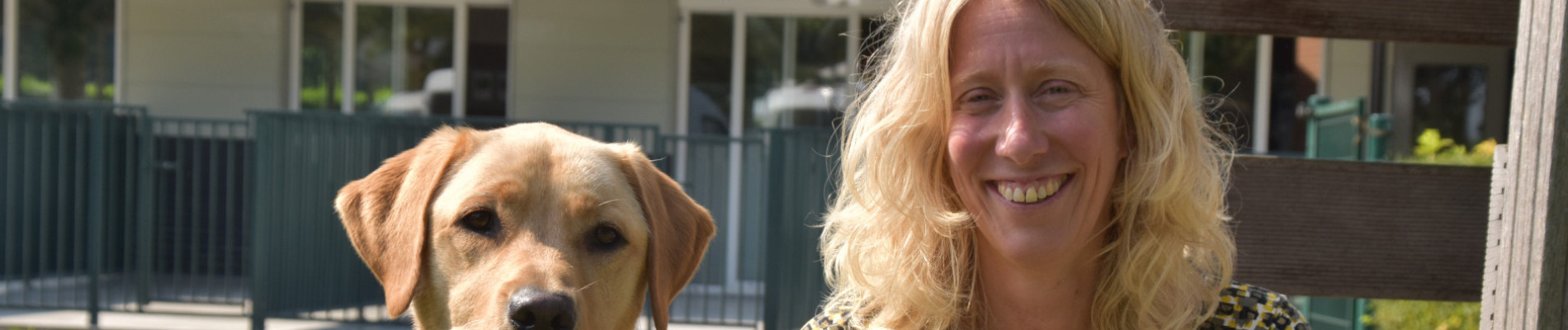 Patricia zit met een blonde hond voor een prachtige groene weide.