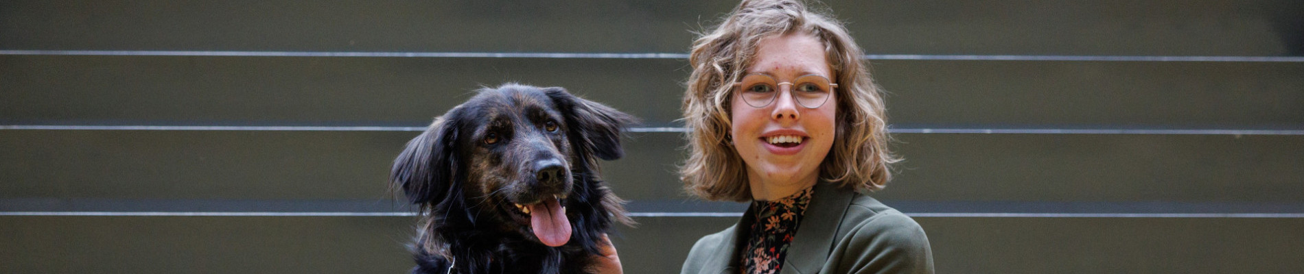 jonge vrouw zit op een trap met haar geleidehond naast zich