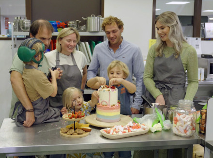 familie van kessel, mercedes en Jamie staan in een keuken en er worden versieringen op de taart aangebracht door de kinderen