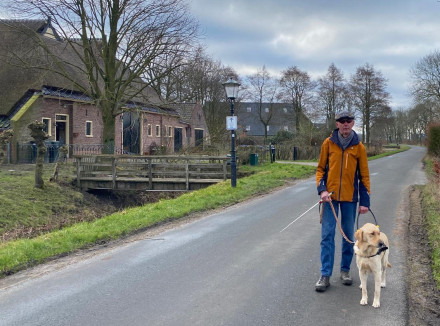 Albert en zijn geleidehond op een rustige landelijke weg