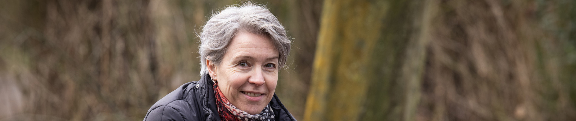Tessa leunt buiten in een bos naar voren over een balustrade