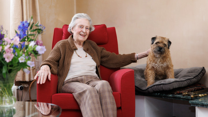 Portret van mevrouw in haar woonkamer met een hond naast haar