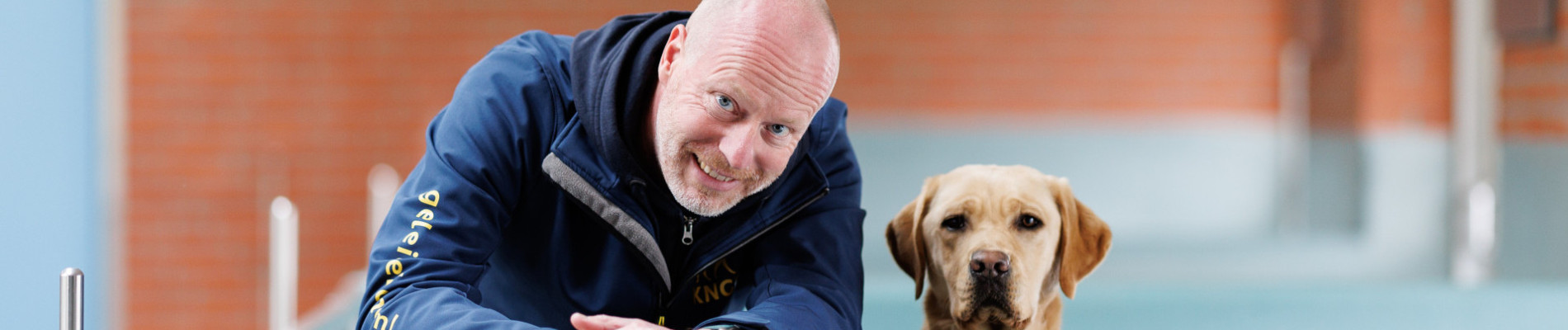 Collega ronald en een labrador kijken samen over een van de muurtjes in de kennel