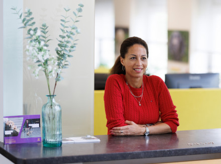 Maureen staat achter de balie bij de receptie