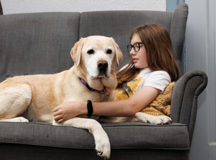 Een jongen en zijn blonde labrador liggen op de bank