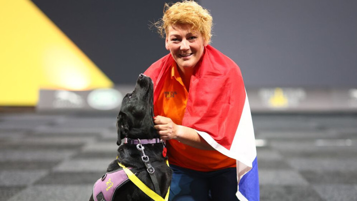 Joyce met haar buddyhond, een vlag en bronzen medaille