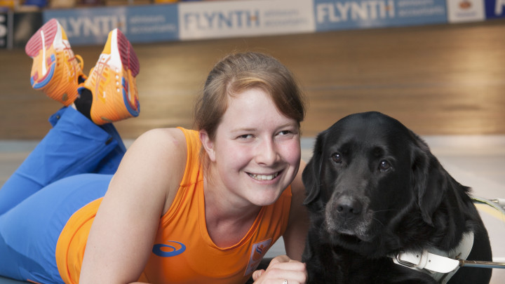 Larissa Klaassen liggend op de vloer in een sportzaal naast haar blindengeleidehond