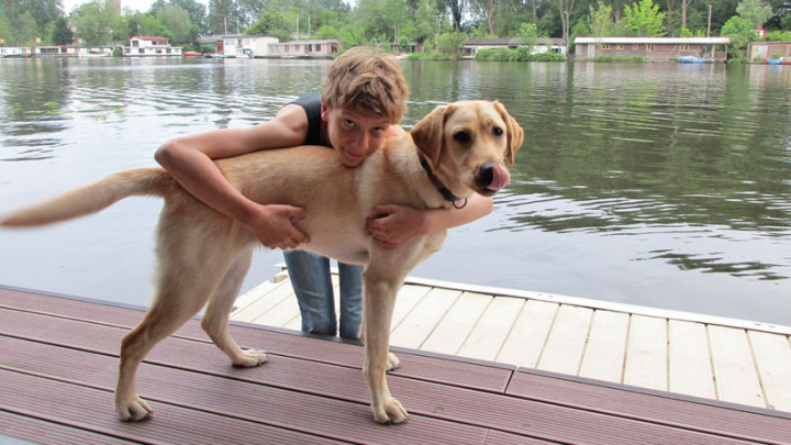 Jongetje knuffelt met hond aan het water