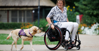 Client in rolstoel met naast haar een hond in tuig