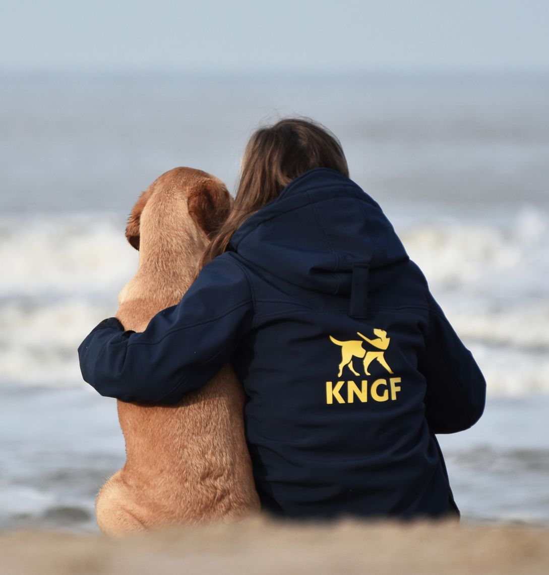 geleidehond en trainer kijken uit over de zee