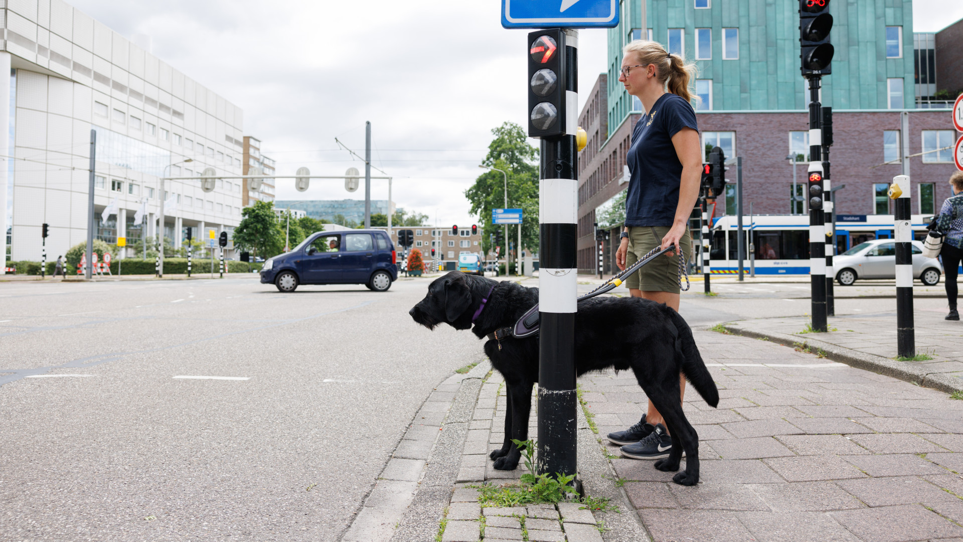 Anna staat buiten bij een stoplicht stil met naast haar een hond in tuig
