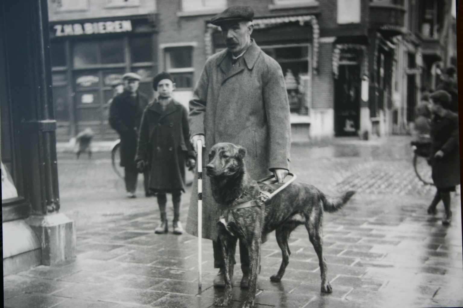 oude zwart-wit foto van een man met zijn geleidehond op straat