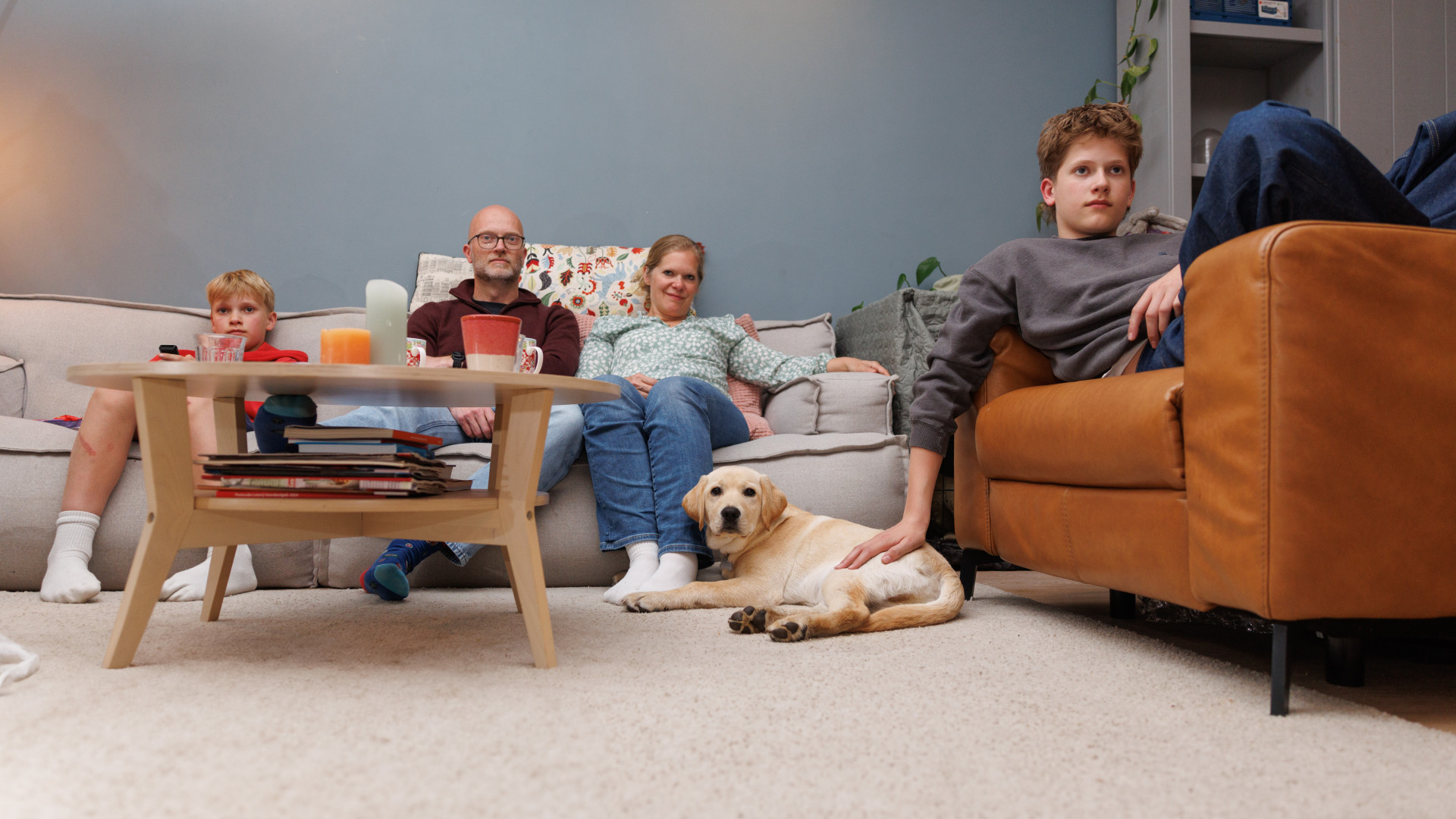 Het gezin in de woonkamer kijkt tv samen met pup Ulay