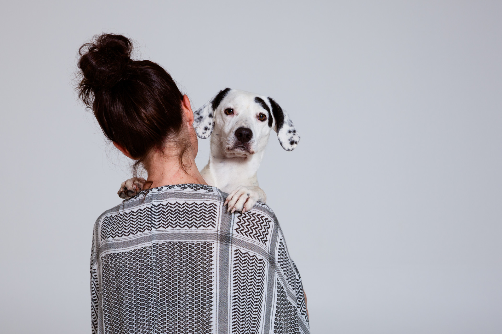 Foto waarbij je Anne op haar rug ziet en een hondje over haar schouder de camera in kijkt