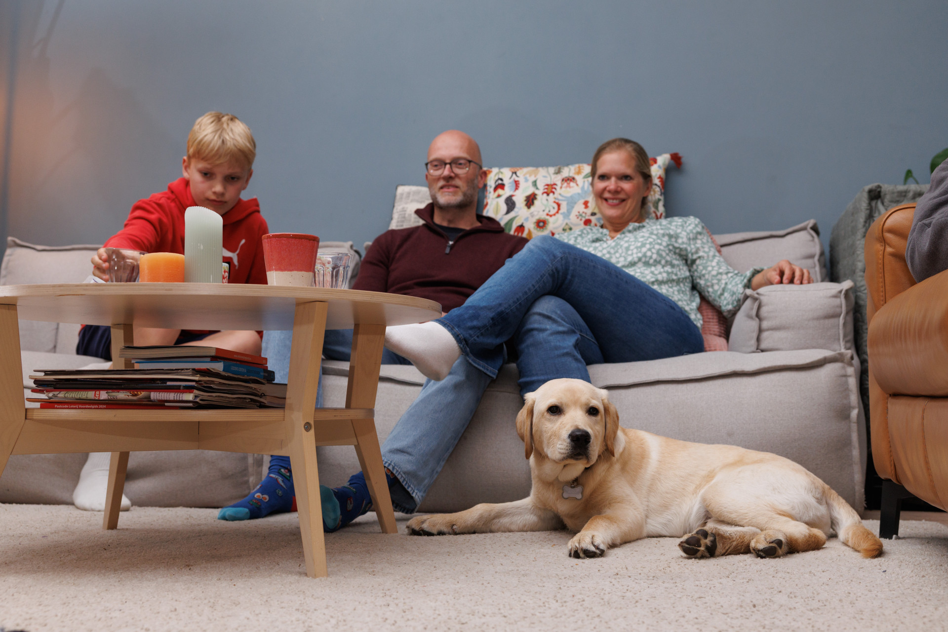 Het gezin in de woonkamer kijkt tv samen met pup Ulay