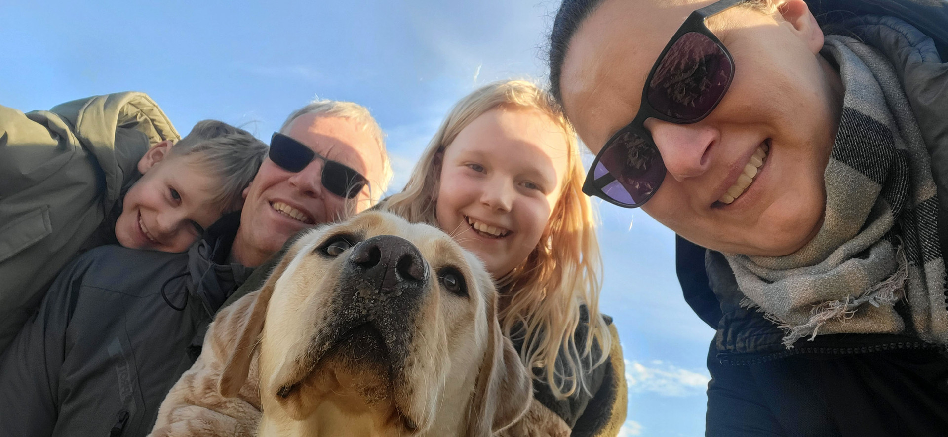 Zonnige groepsfoto van het gezin met de blonde hond.