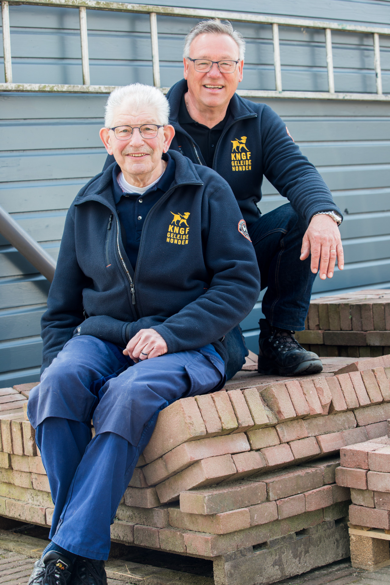 twee vrijwilligers zittend op houten pallets