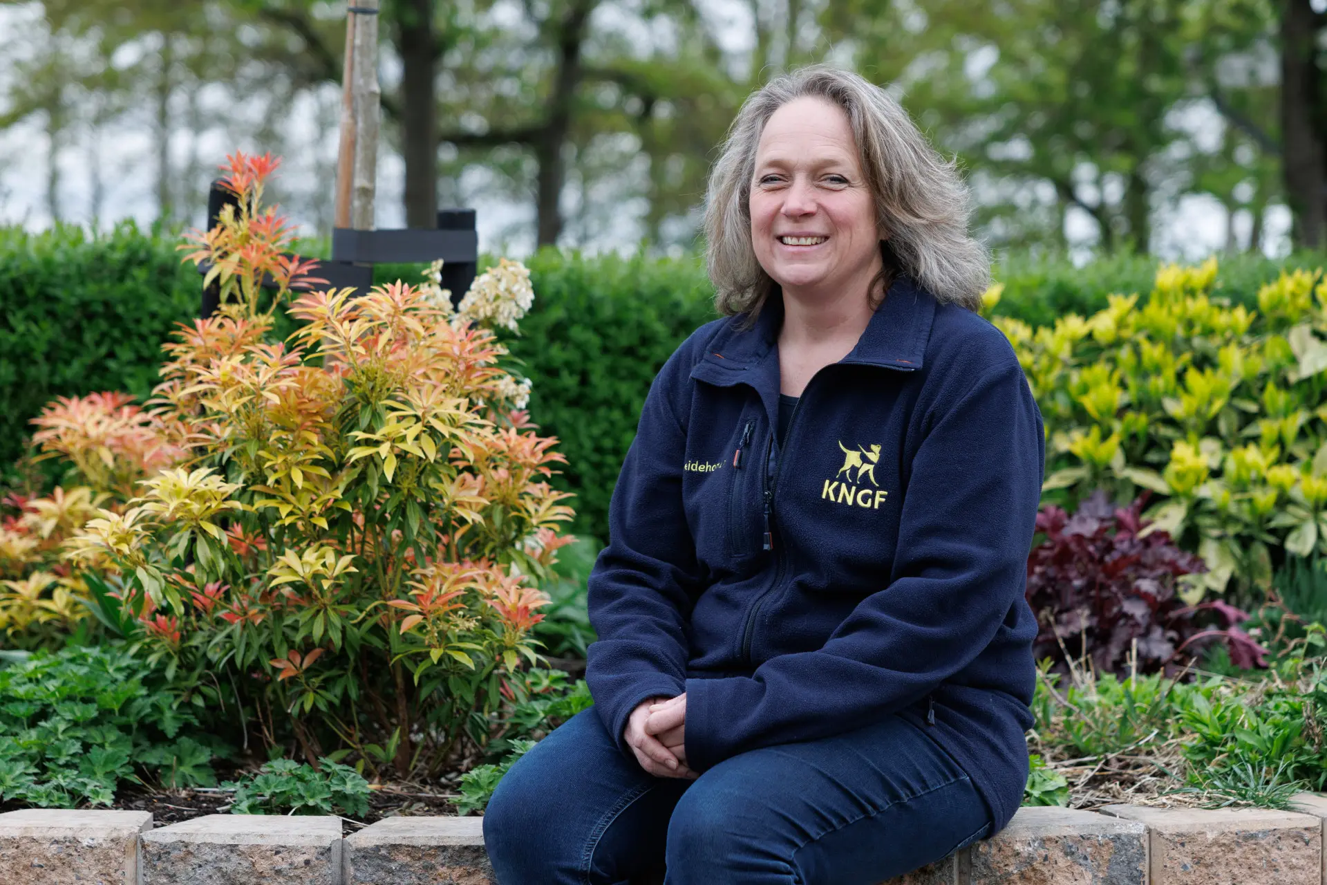 vrouw zit buiten in tuin en KNGF-kleding