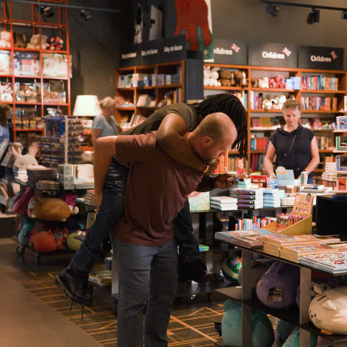 man loopt met man op rug door boekenwinkel