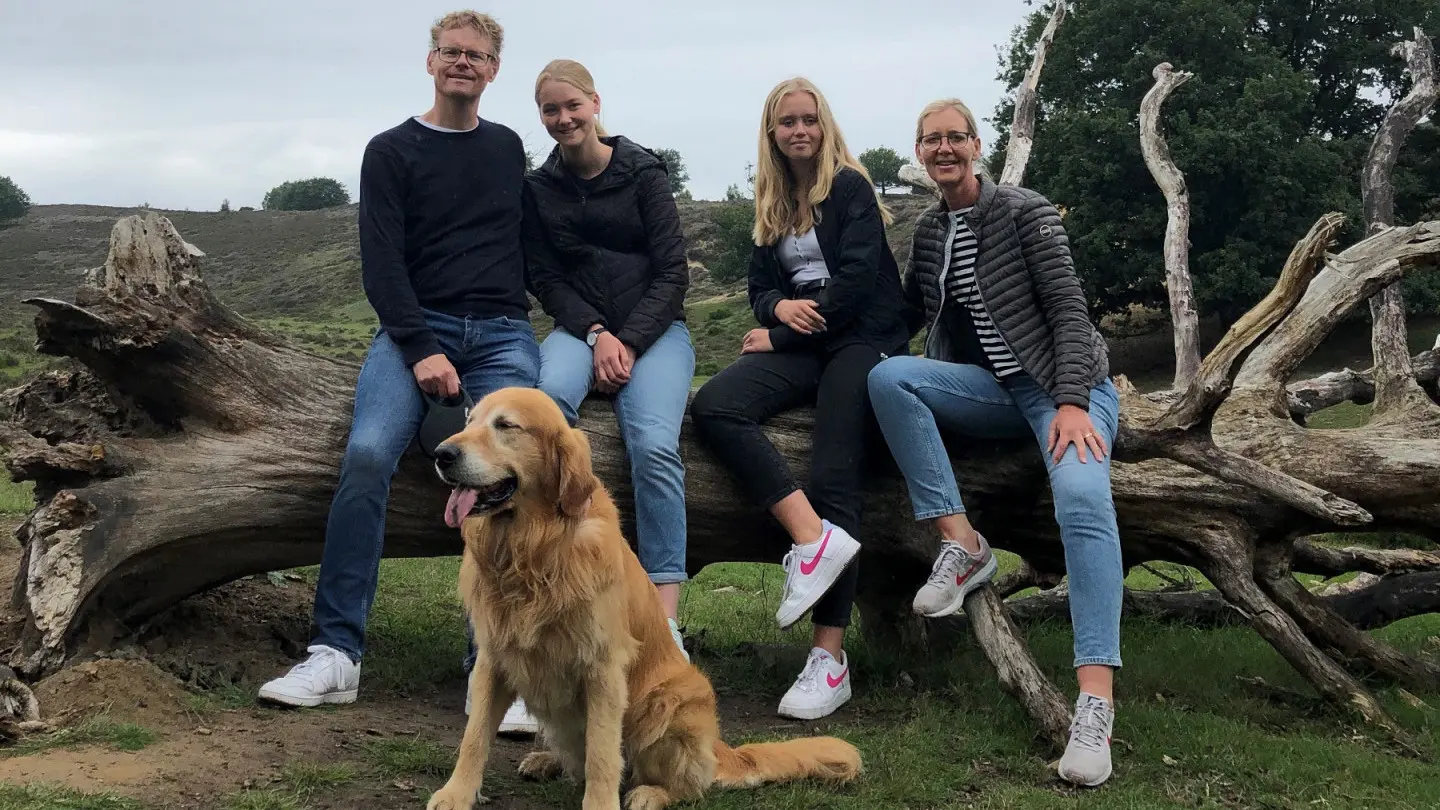 Familie Bolmeijer zittend op een boomstam, met op de voorgrond vaderhond Vledder
